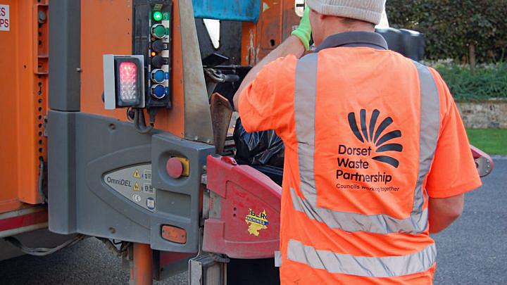 A Dorset Waste Partnership member of staff operates a collection lorry.
