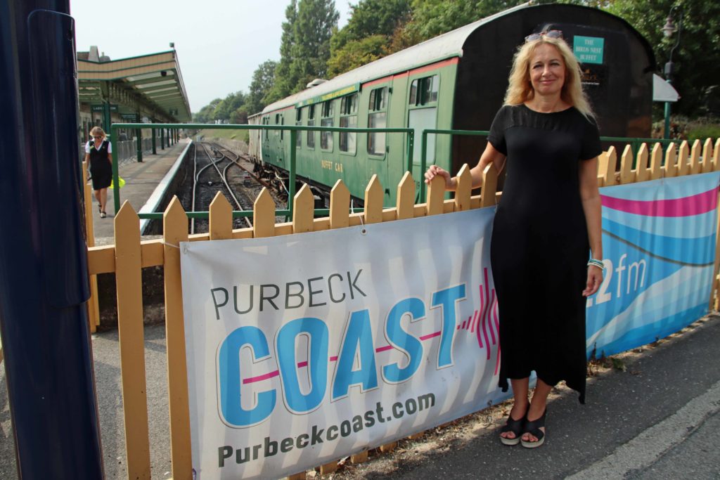 Michelle Langthorne standing by the Purbeck Coast banner