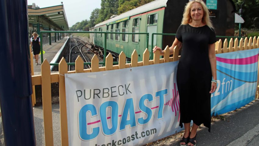 Michelle Langthorne standing by the Purbeck Coast banner