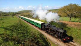 Locomotive pulling carriages through Purbeck countryside