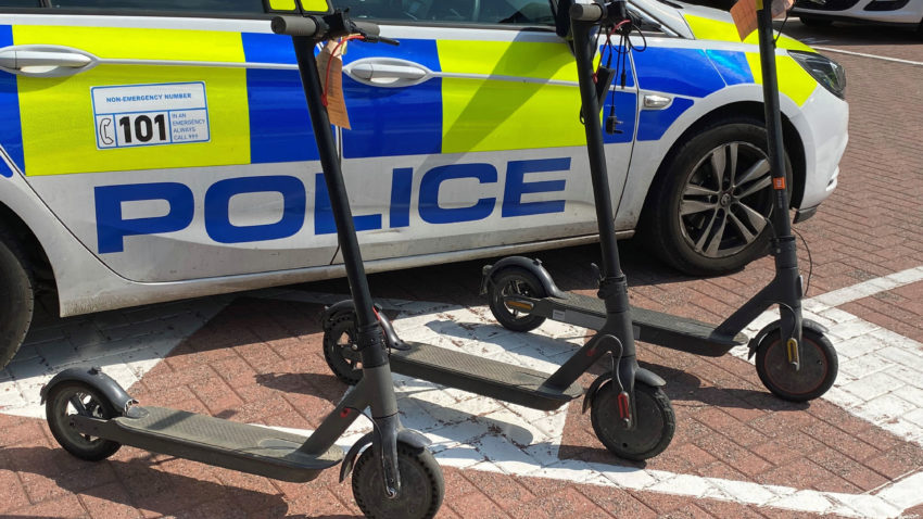 Three e-scooters next to police car
