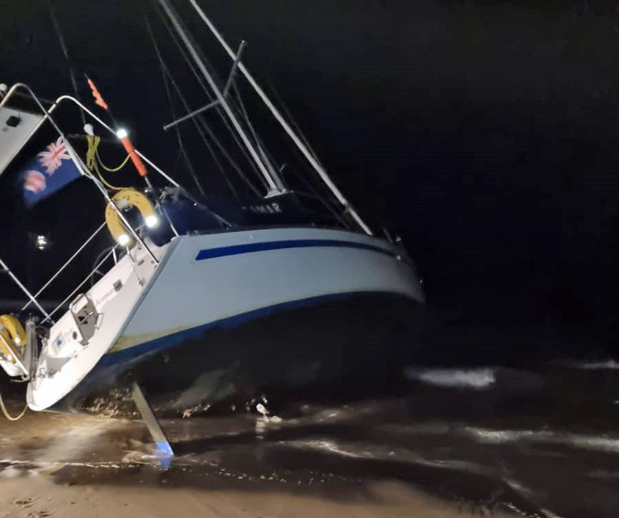 Yacht stranded on Studland beach at night