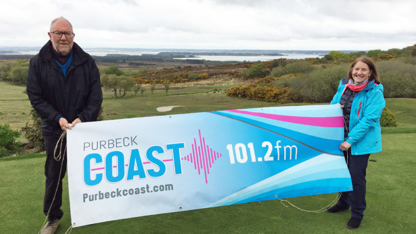 Sports presenters with Purbeck Coast banner on golf course