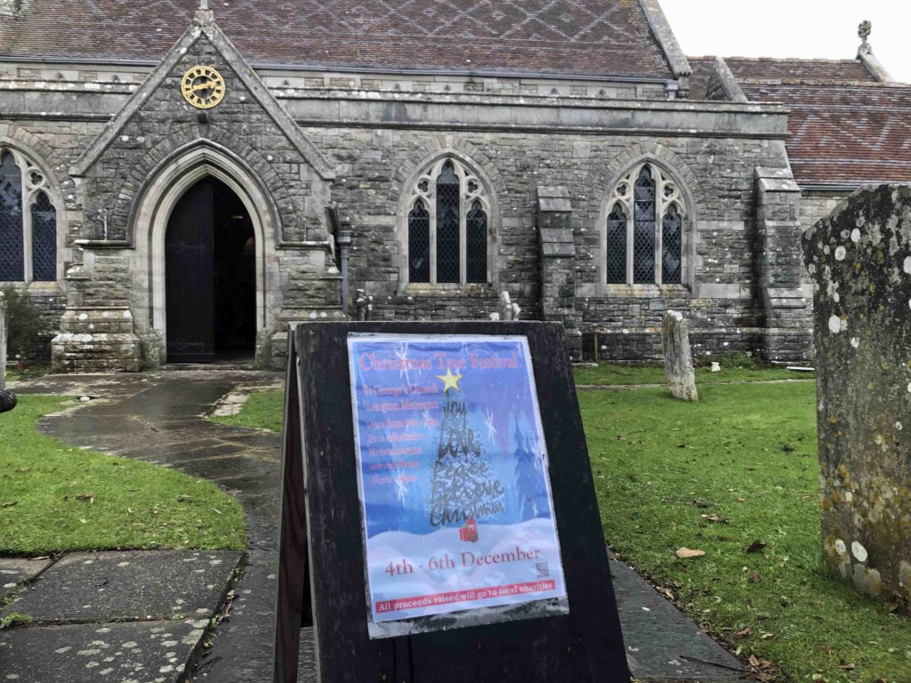 outside St George's Church with poster for Purbeck Christmas Tree Festival