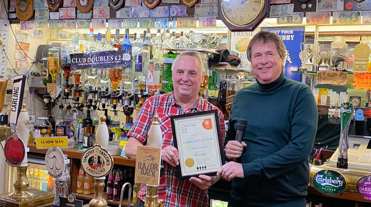 Corfe Castle Club steward Brian Chubby Varney is presented with a framed award for the best Wessex real ale club