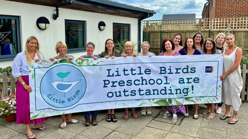 Little Birds staff team with banner